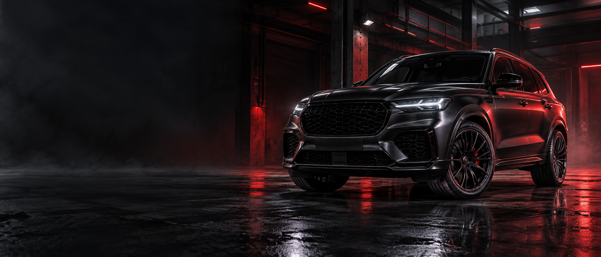 Black performance SUV with premium wheels in a dark red-lit garage